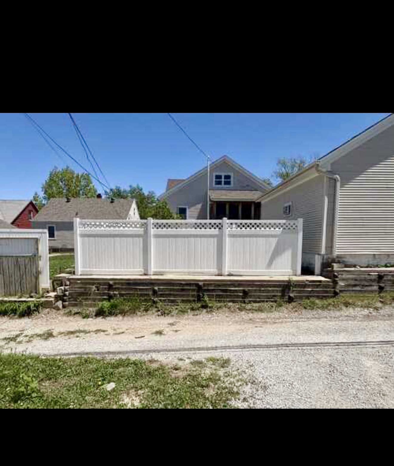 Completed white vinyl privacy fence with decorative lattice top