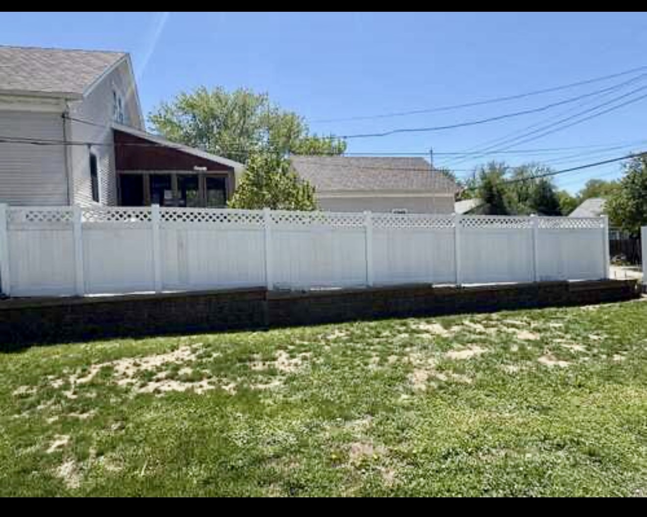 Completed white vinyl privacy fence with lattice accent along a residential yard