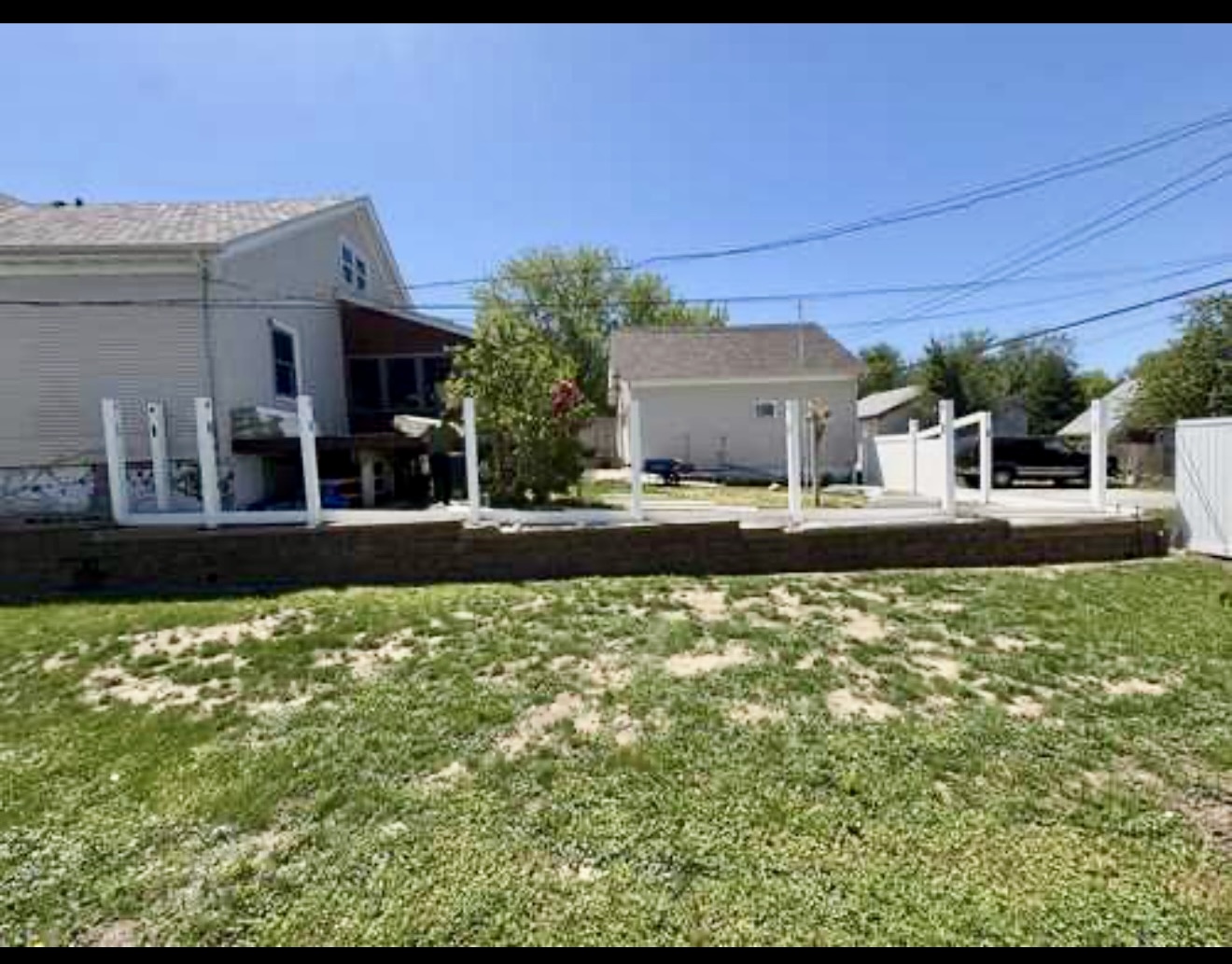 White vinyl fence installation in progress along a residential retaining wall